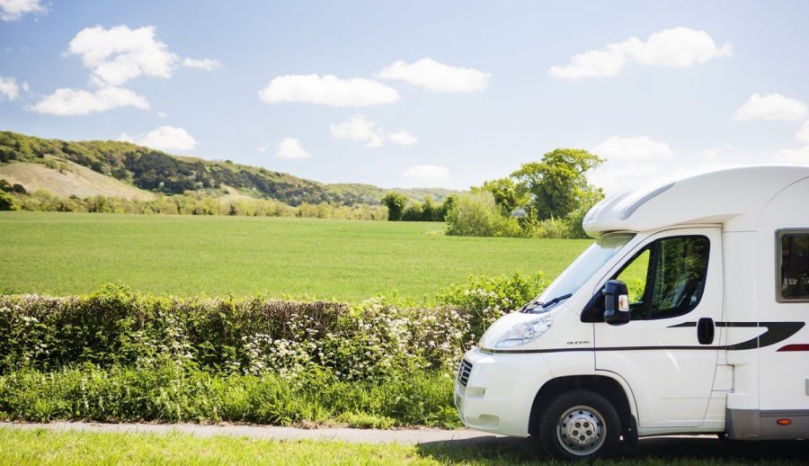 white motorhome in front of green fields with blue sky